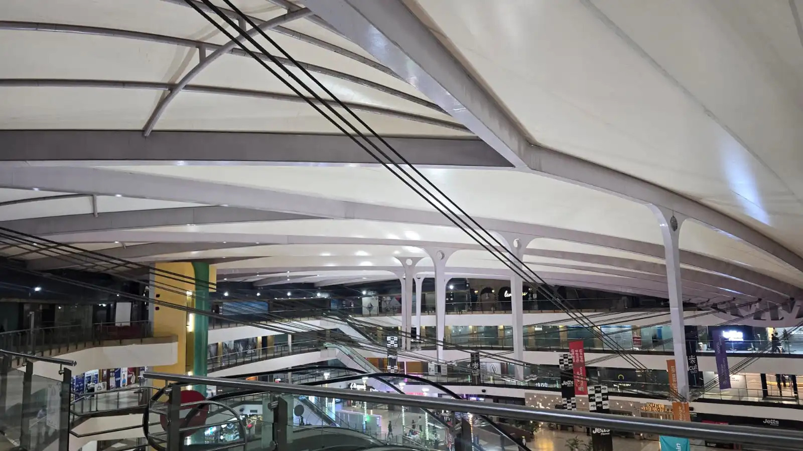 Vasant Square Mall Vasant Kunj — the faceted white membrane panels seen from an upper retail level after dark, Ekra Decor tensile roof